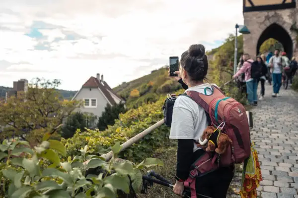 Frau macht Foto auf Wanderung bei Stuttgart. Weinberge und Häuser im Hintergrund.